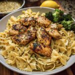 A delicious plate of Cowboy Butter Lemon Bowtie Chicken Pasta with Broccoli, featuring grilled chicken pieces and vibrant green broccoli florets.