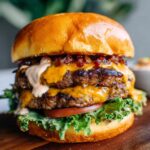 Close-up of a juicy double patty Crack Burger with melted cheese, lettuce, tomato, and sauce.