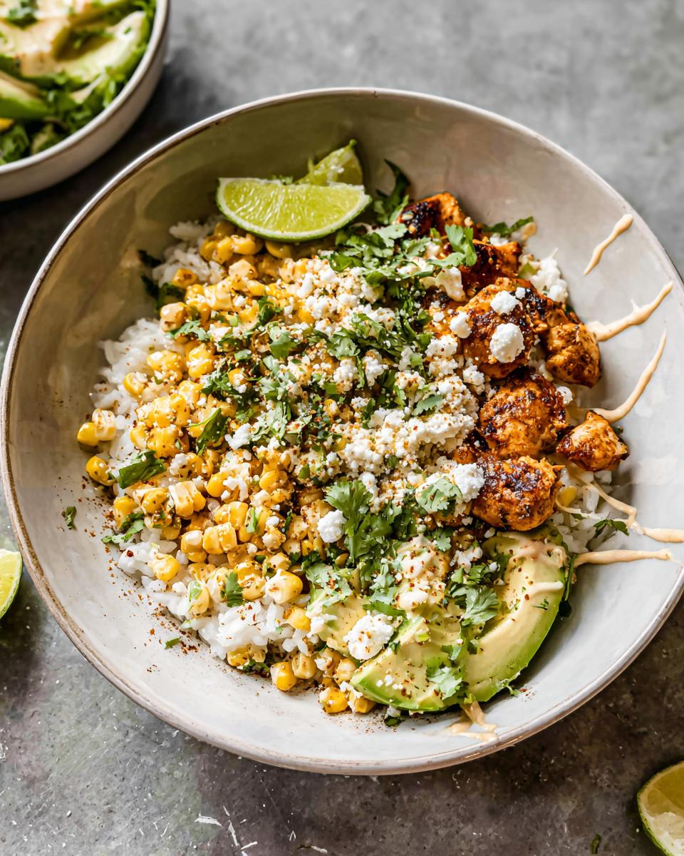 A vibrant Easy Street Corn Chicken Bowl filled with rice, grilled chicken, corn, avocado, crumbled cheese, and cilantro, topped with lime wedges.