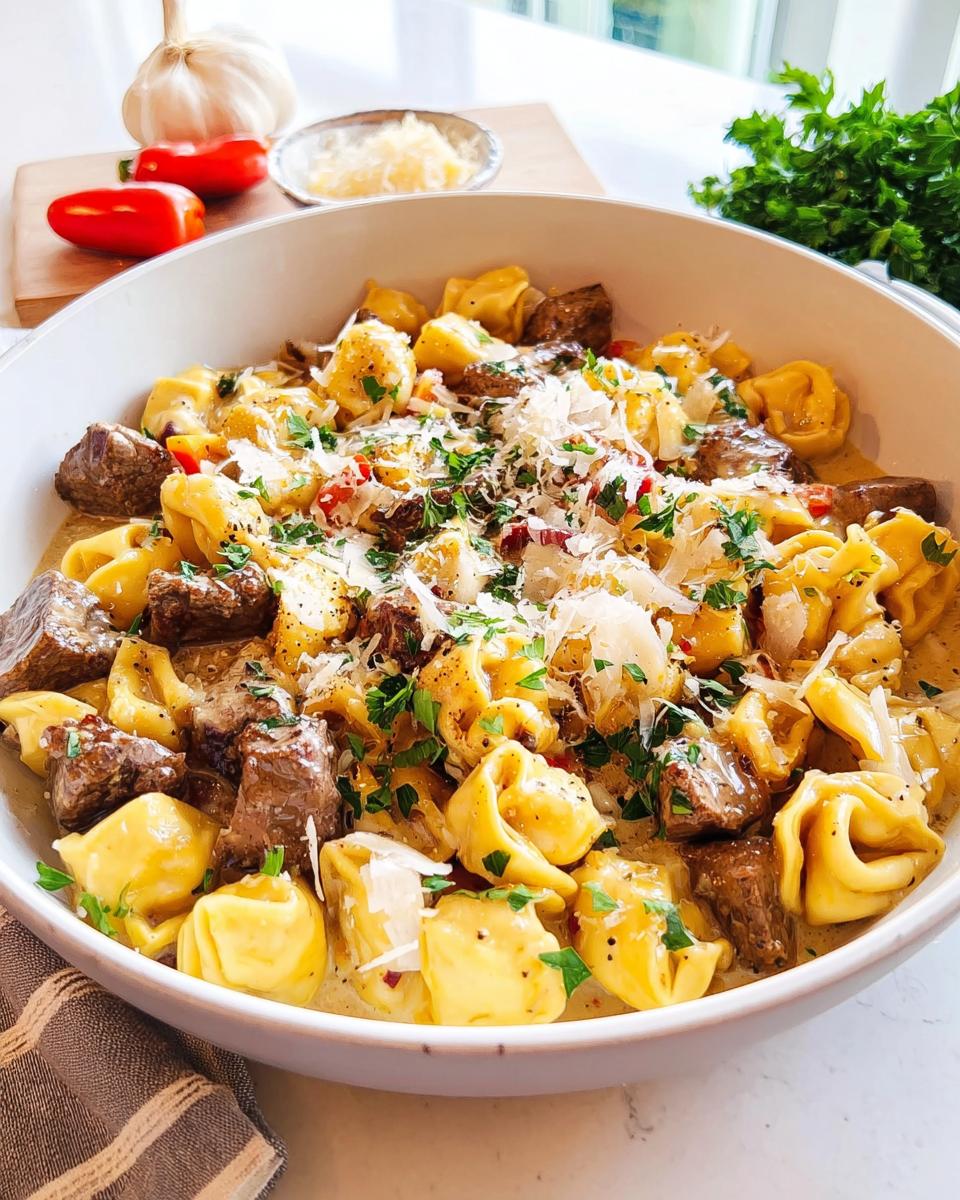 A close-up of a bowl filled with Speedy Garlic Steak Tortellini, topped with parmesan cheese and parsley.