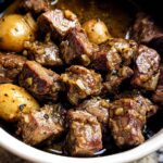 Close-up of tender High Protein Slow Cooker Garlic Butter Beef Bites with small potatoes in a rich sauce.
