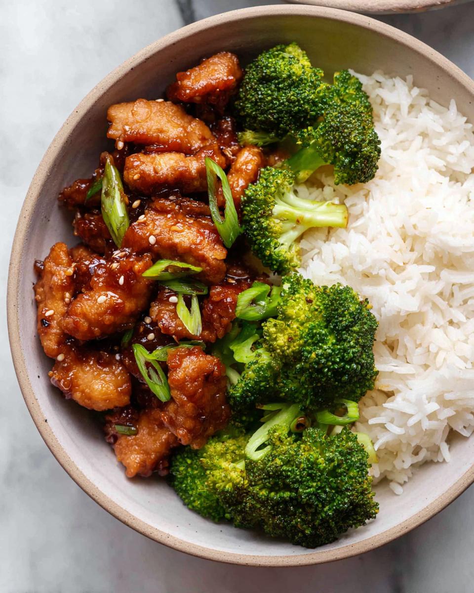 A delicious Honey Garlic Pork Rice Bowl featuring tender pork pieces, steamed broccoli, and fluffy white rice, garnished with green onions.