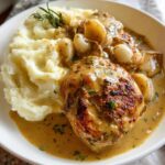 A bowl of Irresistible Garlic Herb Chicken with Creamy Mashed Potatoes, garnished with rosemary.