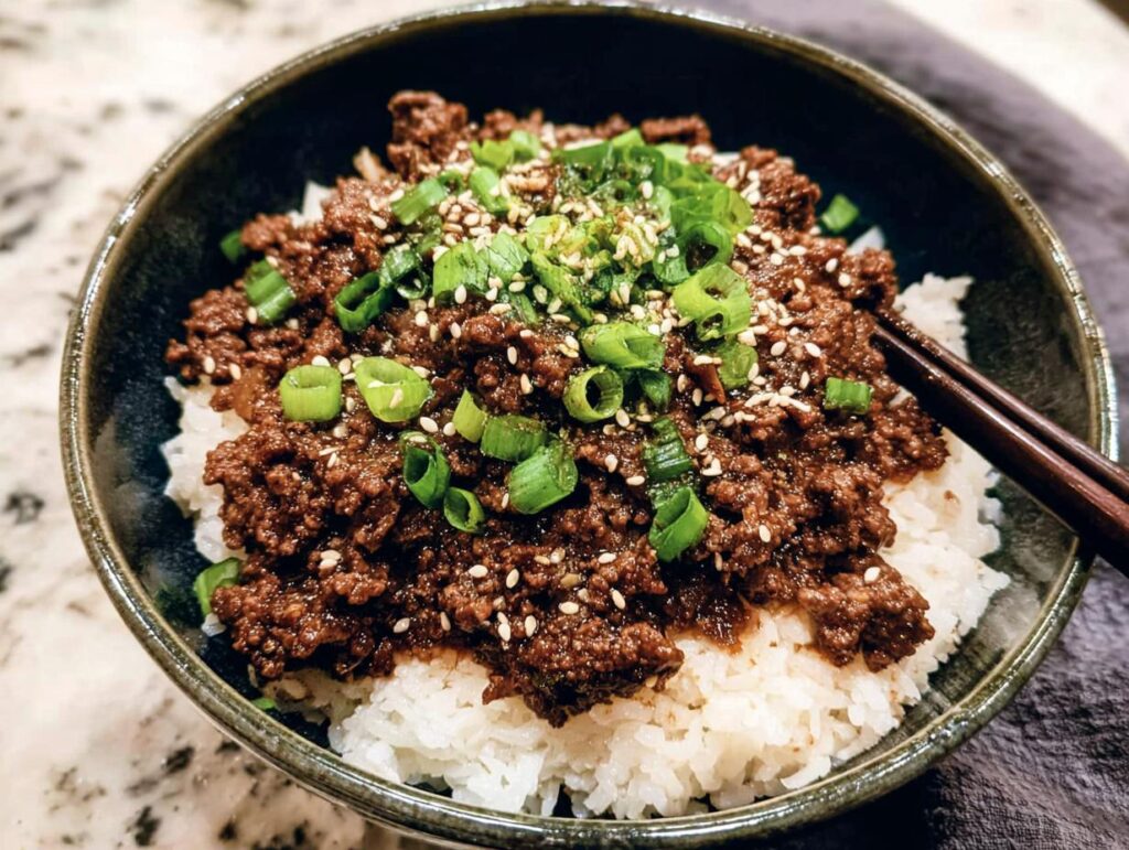 A close-up of a Korean Ground Beef Bowl topped with sesame seeds and chopped green onions, served over white rice.