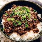 A close-up of a Korean Ground Beef Bowl topped with sesame seeds and chopped green onions, served over white rice.