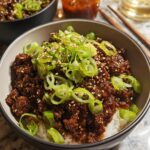 A close-up of a Korean Ground Beef Bowl filled with savory ground beef over white rice, topped with fresh green onions and sesame seeds.