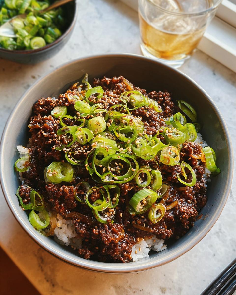 A close-up of a Korean Ground Beef Bowl served over white rice, topped with fresh scallions and sesame seeds.