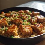 A close-up of One-Pan Honey BBQ Chicken Rice in a black skillet, topped with chopped green onions.