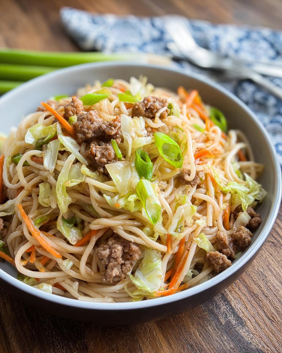 A close-up of a Potsticker Noodle Bowl with Pork & Cabbage, featuring noodles, ground pork, shredded cabbage, and carrots.