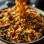 A close-up of a steaming Potsticker Noodle Bowl with Pork & Cabbage Slaw, showing noodles, pork, and vegetables.