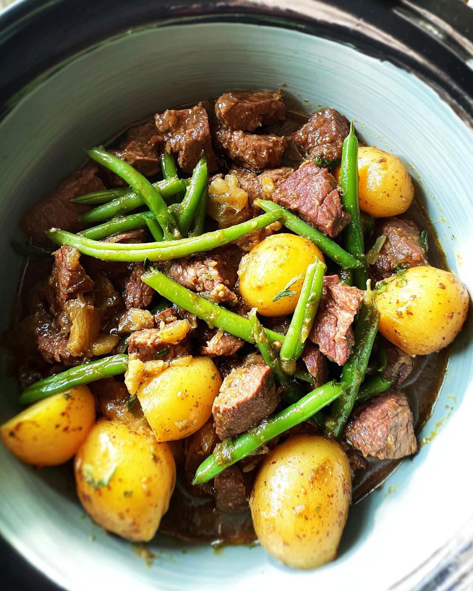 A bowl of Slow Cooker Garlic Butter Beef with Potatoes and green beans, showcasing tender beef chunks and whole baby potatoes.