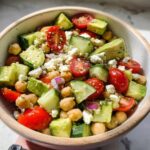A vibrant bowl of Chickpea Feta Avocado Salad with cherry tomatoes, cucumber, and red onion.