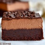A close-up of a decadent Chocolate Mousse Brownie slice, showcasing the brownie base, chocolate mousse layer, and chocolate ganache topping.