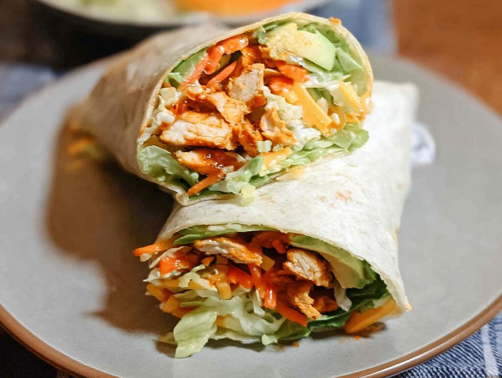 A delicious wrap filled with creamy spinach, eggs, chicken, avocado, cheese, and shredded carrots.