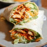 A delicious wrap filled with creamy spinach, eggs, chicken, avocado, cheese, and shredded carrots.