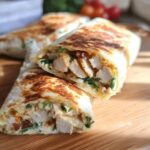 A close-up of a perfectly grilled Crispy Chicken Bacon Wrap, sliced in half to reveal tender chicken, bacon, and greens.