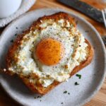 A single serving of crispy feta fried eggs on toasted bread, seasoned with black pepper.