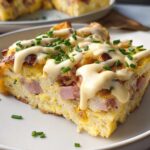 A delicious slice of Easy Eggs Benedict Casserole topped with creamy sauce and chives.