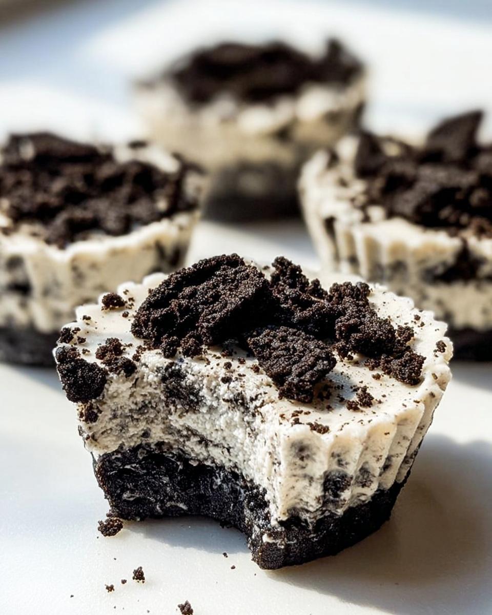 A close-up of a Healthy No-Bake Oreo Cheesecake Bite with a bite taken out, showing the creamy filling and cookie crust.