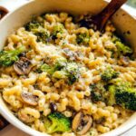 A close-up of Healthy One Pot Broccoli Mac & Cheese in a serving bowl, featuring pasta, broccoli florets, and sliced mushrooms.