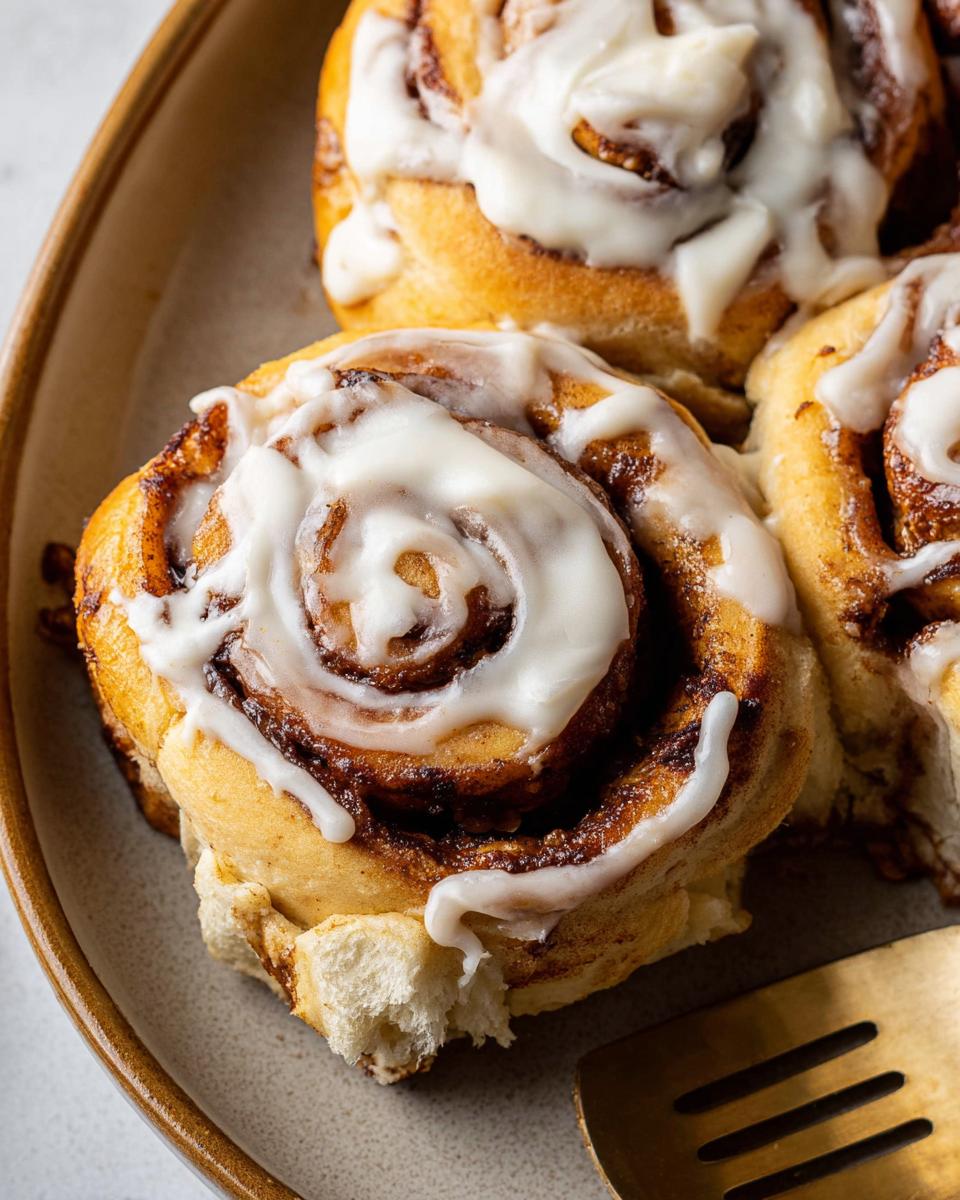 Close-up of a fluffy high-protein cinnamon roll bread swirl, generously topped with white icing.