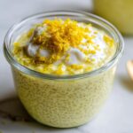 A close-up of a glass jar filled with creamy Lemon Cream Chia Pudding, topped with yogurt and lemon zest.