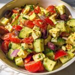 A bowl of Simple & Zesty Mediterranean Avocado Egg Salad with tomatoes, cucumbers, feta, olives, and avocado.