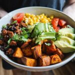 A vibrant Sweet Potato Taco Bowl filled with roasted sweet potatoes, black beans, corn, avocado, and tomatoes.