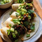 Close-up of delicious Thai Basil Beef Rolls served on a tortilla with fresh cucumber, mint, and chopped peanuts.