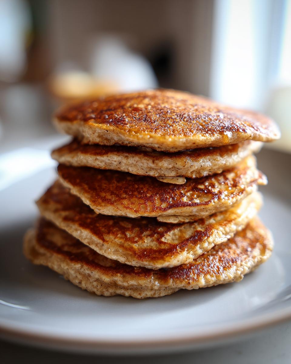 A close-up shot of a stack of golden-brown banana oat pancakes on a plate, perfect for breakfast ideas.