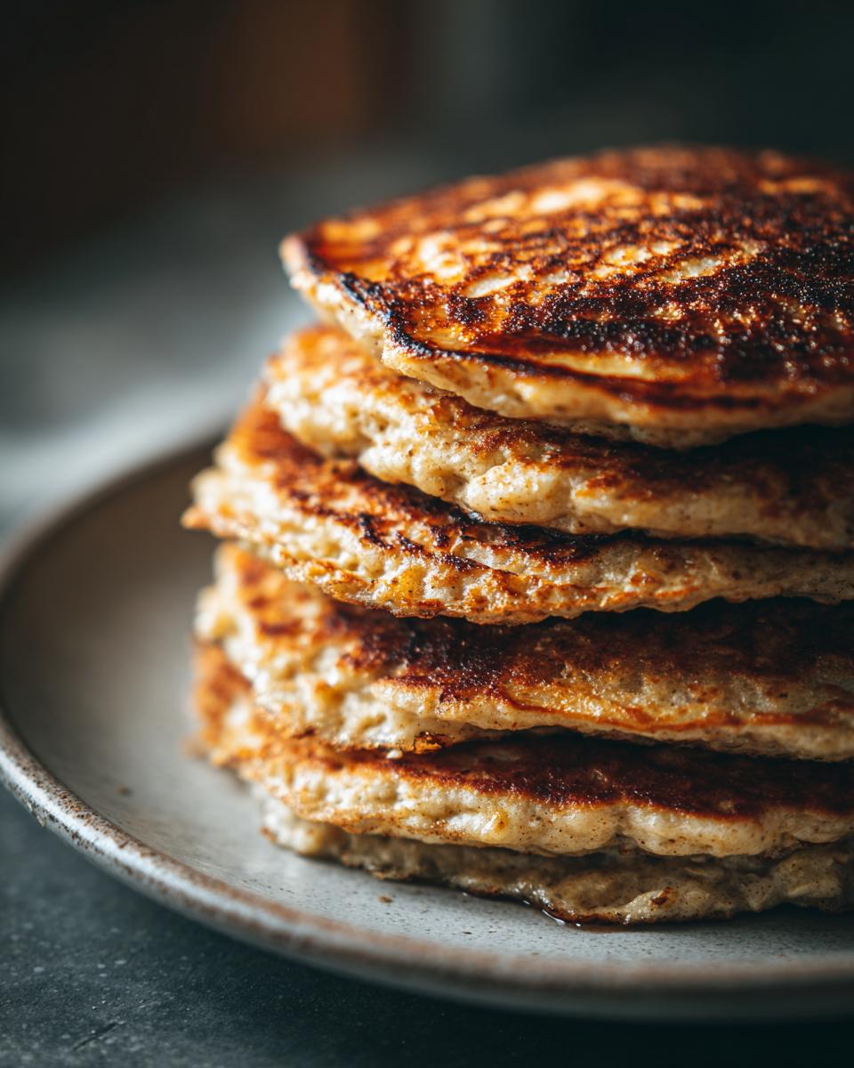 Close-up of a stack of golden-brown banana oat pancakes on a plate, showcasing their fluffy texture.