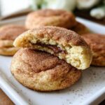 A close-up of a chewy churro cookie, split in half to reveal a rich chocolate filling.
