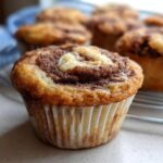 Close-up of a delicious Cinnamon Roll Protein Muffin with a swirl of cinnamon sugar on top.