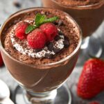 A close-up of Easy Cottage Cheese Chocolate Mousse topped with whipped cream, raspberries, mint, and chocolate shavings.