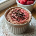 A close-up of a creamy Cottage Cheese Raspberry Mousse topped with chocolate shavings in a white ramekin.