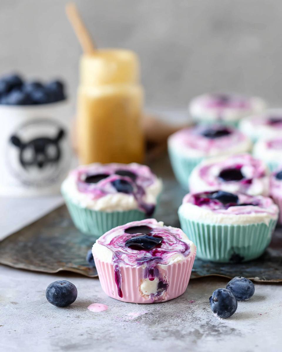 Close-up of easy blueberry swirl yogurt bites in colorful cupcake liners, topped with blueberry sauce.