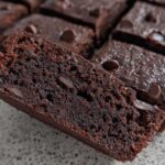 Close-up of a rich, dark chocolate Greek Yogurt Brownie slice with visible chocolate chips.
