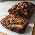 A slice of moist High Protein Chocolate Banana Bread with visible chocolate chips and banana swirls.
