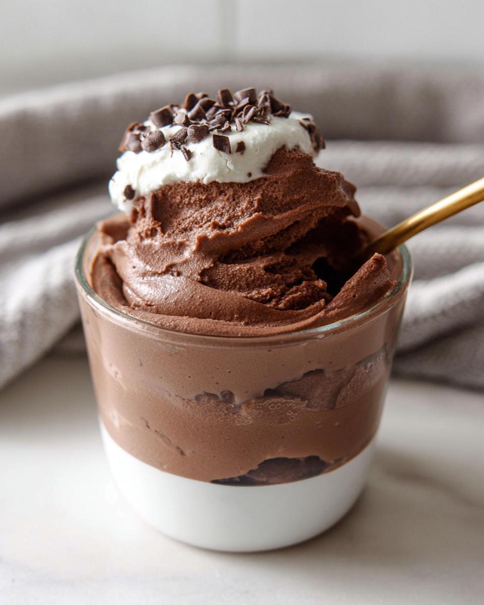 Rich chocolate High-Protein Cottage Cheese Peanut Butter Mousse topped with whipped cream and chocolate shavings in a glass.