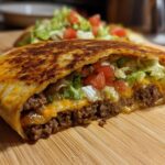 A delicious homemade crunchwrap filled with seasoned ground beef, melted cheese, lettuce, and tomatoes.