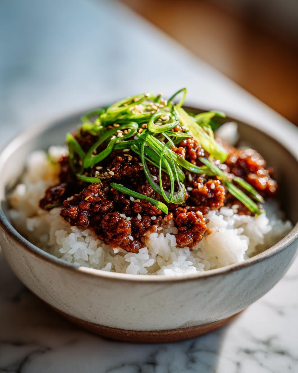 A close-up of a Korean beef rice bowl with seasoned ground beef, white rice, and green onions.