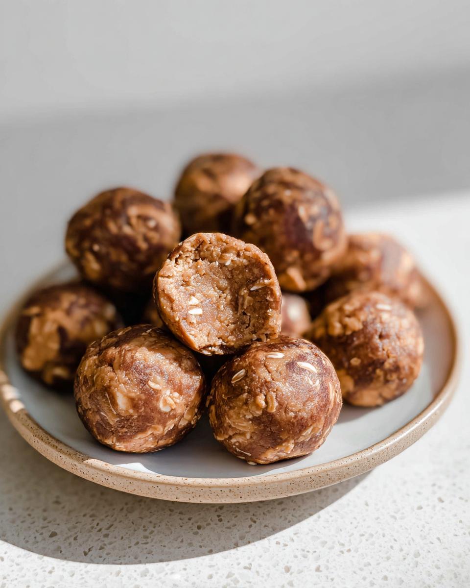 Close-up of No-Bake Chocolate Peanut Butter Protein Balls on a plate, one is broken in half.