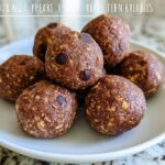 A pile of No-Bake Chocolate Peanut Butter Protein Balls with chocolate chips on a white plate.