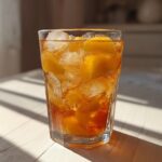 A refreshing glass of Peach Recipes With Iced Tea Slush filled with ice and peach slices.