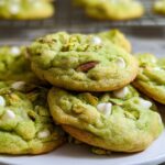 A close-up of soft and chewy pistachio pudding cookies, studded with white chocolate chips and chopped pistachios.