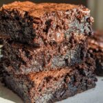 A stack of three rich, dark chocolate Tasty Zero Sugar Brownies with visible chocolate chips.
