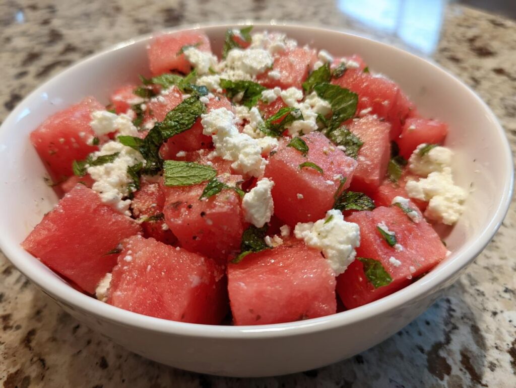 Close-up of a refreshing watermelon recipe with feta cheese and mint in a white bowl, perfect for summer.